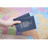 Hand mit zwei Reisepässen vor einer Weltkarte