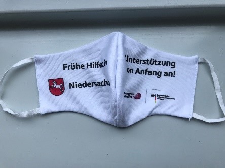 Mund-Nasen-Schutz (beide Seiten zu sehen) mit Aufdruck "Frühe Hilfen in Niedersachsen" und "Unterstützung von Anfang an!"
