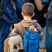 Flüchtlingskind mit Rucksack und Kuscheltier